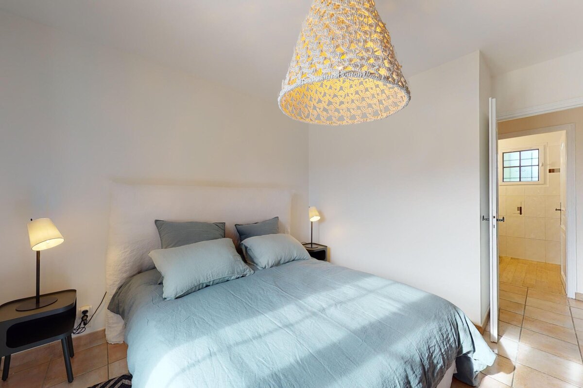 A bedroom with a bed and a lamp hanging from the ceiling