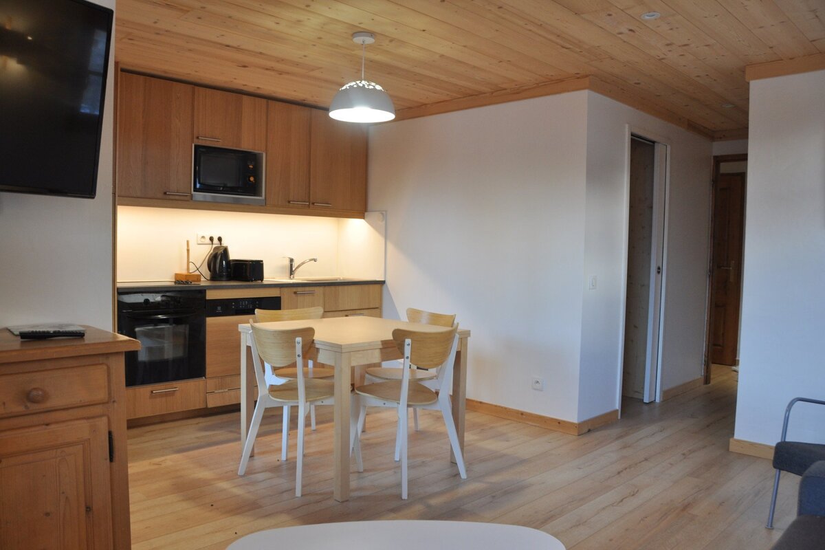 A kitchen with wooden cabinets and a table and chairs