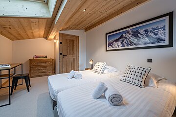 A bedroom with two beds and a picture of a mountain on the wall
