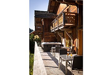 A wooden deck with tables and chairs and a hot tub