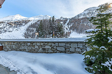 A stone wall surrounded by snow with mountains in the background