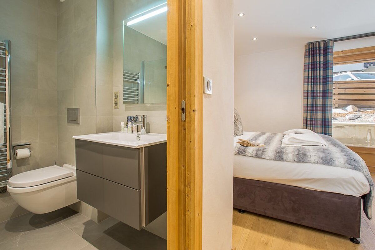 A bathroom with a toilet and a sink next to a bed