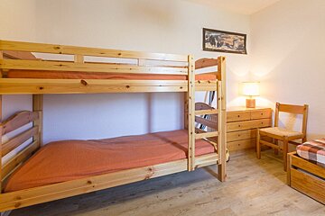 A bunk bed in a bedroom with a picture on the wall above it