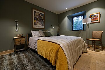 A bedroom with a bed a nightstand and a painting on the wall
