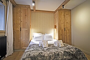 A bedroom with a bed and wooden cabinets