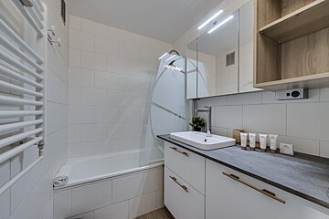 A bathroom with a bathtub and a sink with a few bottles of lotion on the counter