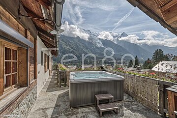 A hot tub on a balcony with a mountain in the background