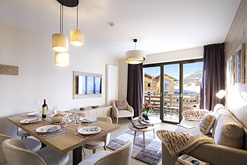 A living room with a table and chairs and a bottle of wine