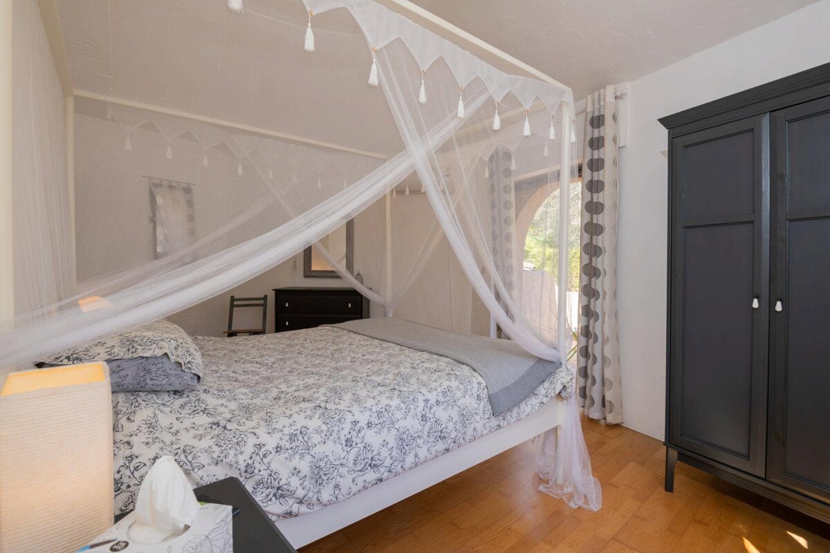 A bedroom with a canopy bed and a black wardrobe