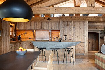 A bowl of fruit sits on a table in a kitchen