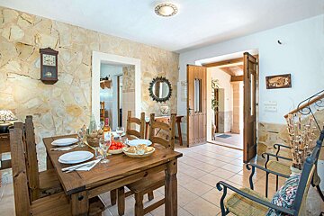 A dining room with a wooden table and chairs and a clock on the wall