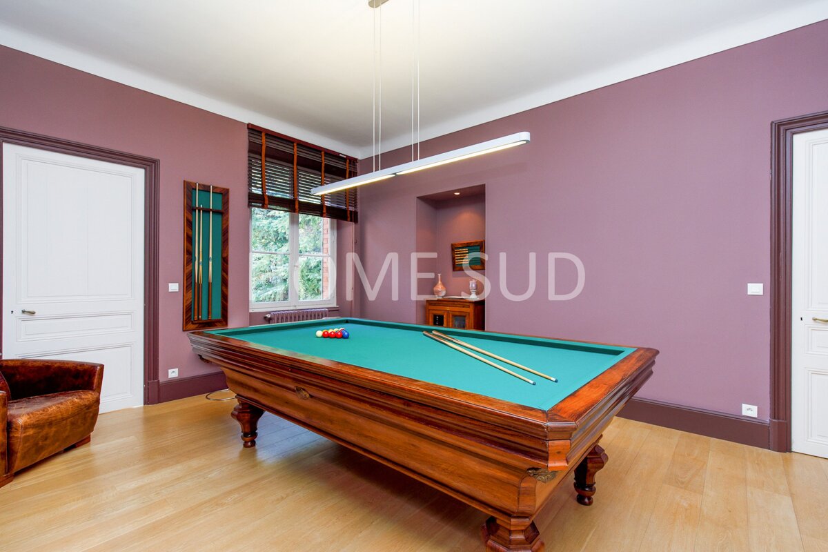 A pool table in a room with purple walls that says mesud