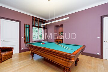 A pool table in a room with purple walls that says mesud