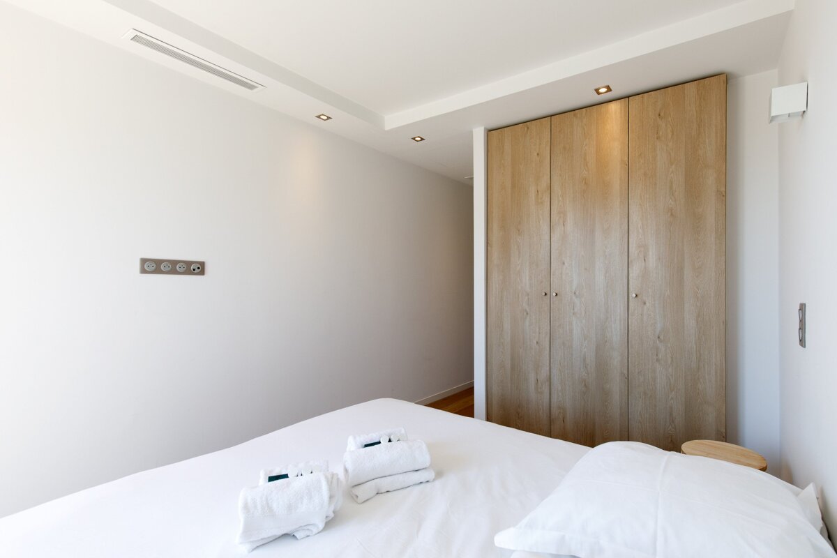 A bedroom with a white bed and a wooden wardrobe