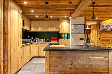 A kitchen with wooden cabinets and a bottle of wine on the counter
