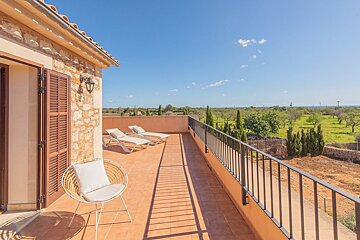 A balcony with chairs and lounge chairs on it