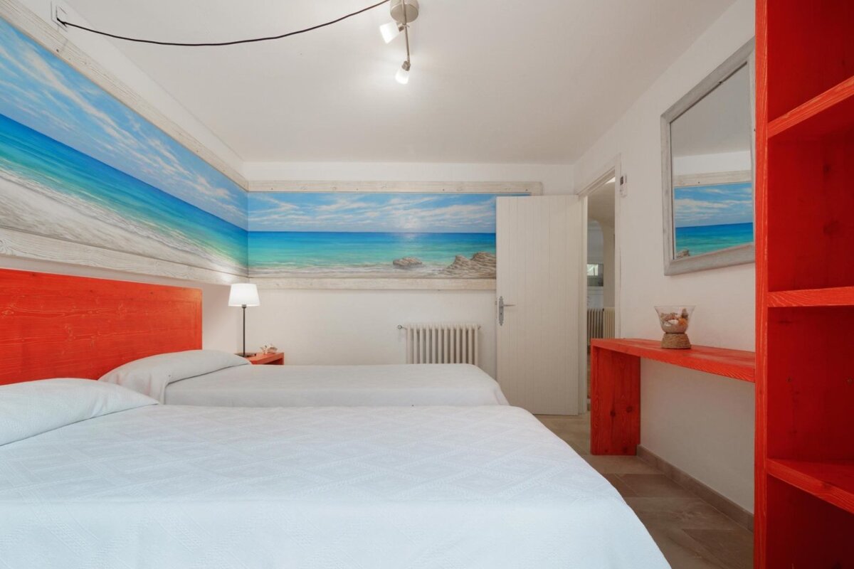 A bedroom with two beds and a painting of the ocean on the wall