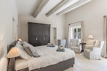 A bedroom with a large bed and two chairs