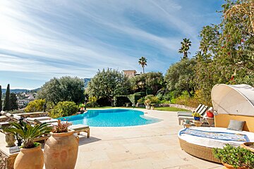 A large swimming pool is surrounded by chairs and plants