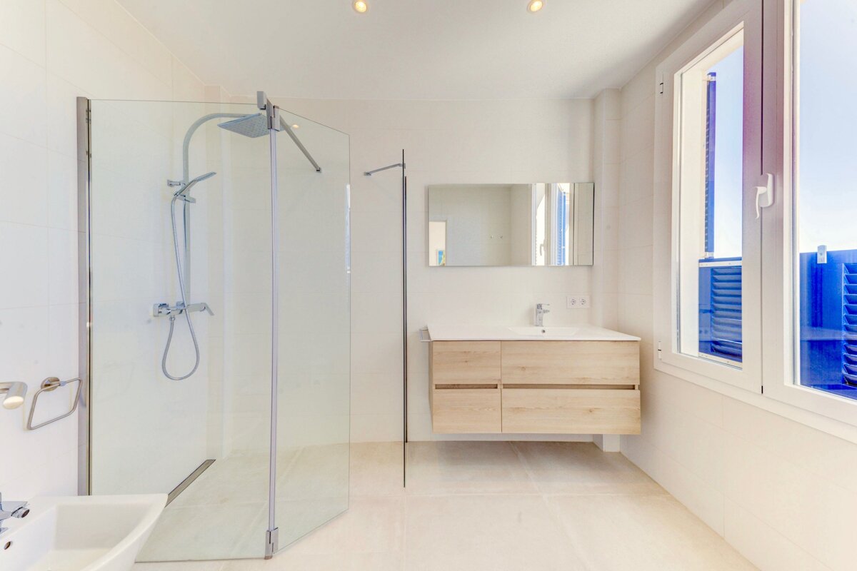 A bathroom with a walk in shower and a sink