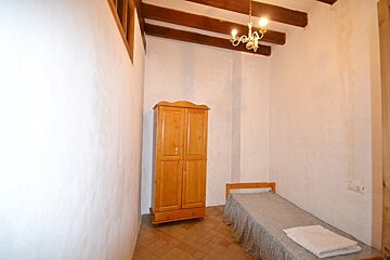 A bedroom with a single bed and a wooden wardrobe