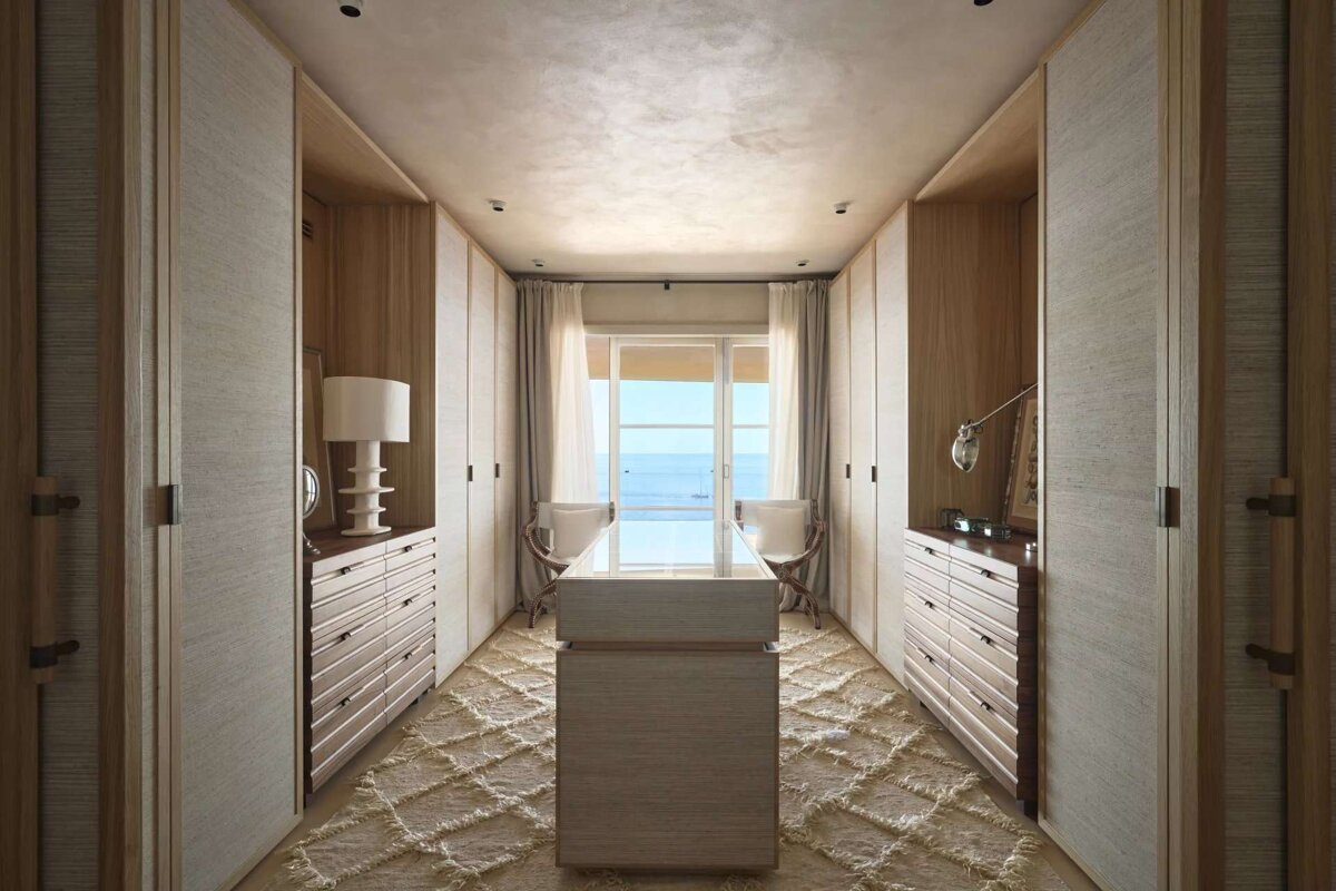 A walk in closet with lots of drawers and a table