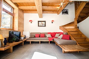 A living room with a couch and stairs and a flat screen tv