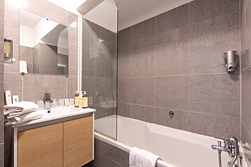 A bathroom with a bathtub a sink and a mirror