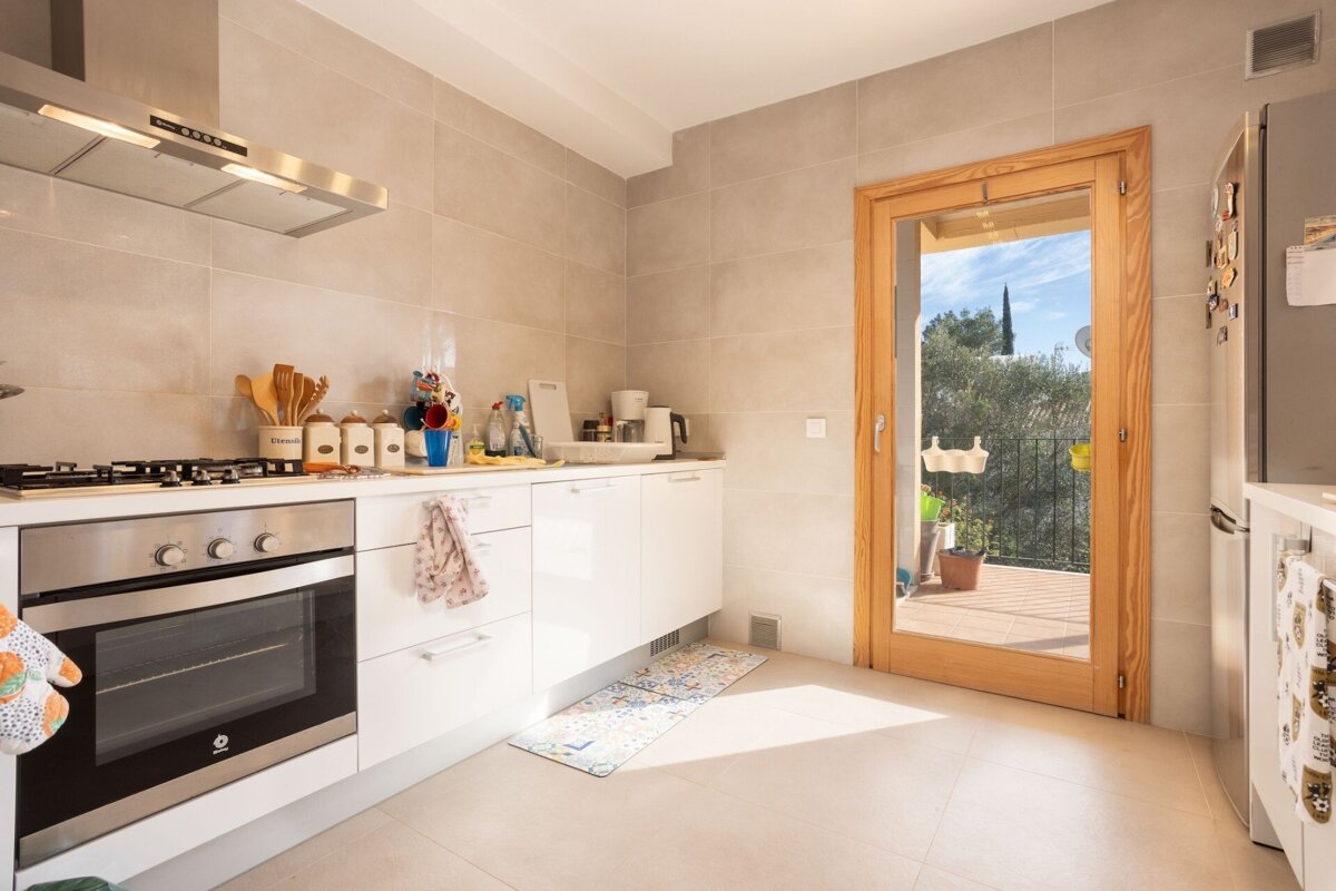 A kitchen with a stainless steel stove top oven and white cabinets