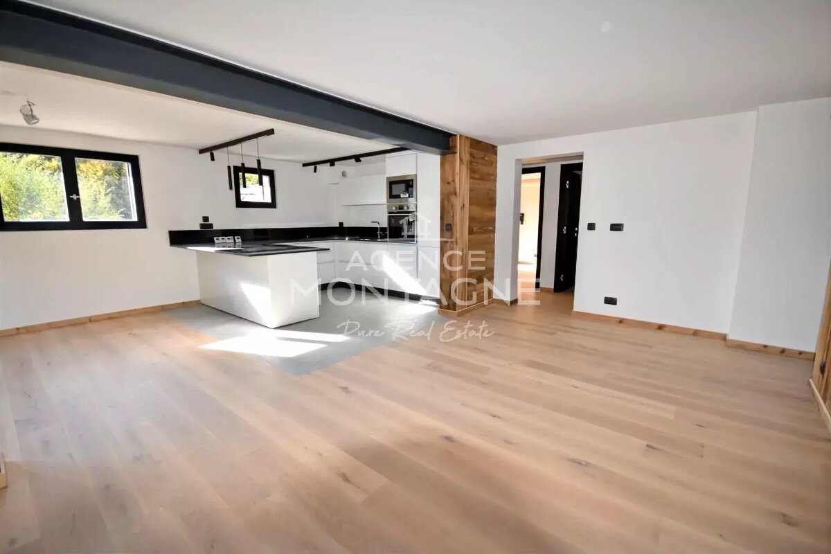 Bright, modern open-plan interior featuring light wood floors and a sleek white kitchen with a central island.
