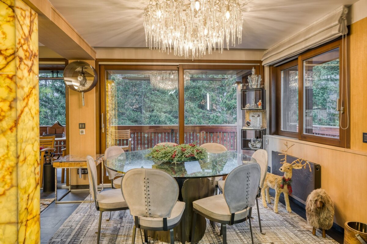 A dining room with a glass table and chairs and a chandelier