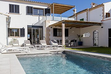 A white house with a swimming pool in front of it
