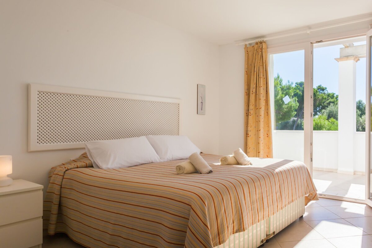A bedroom with a large bed and a balcony