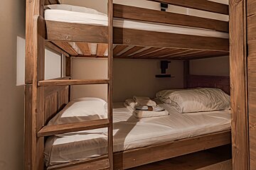 Cozy wooden bunk beds with fresh white bedding. Towels and slippers are neatly stacked on the lower bunk, hinting at a comfortable stay.