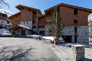 A snowy mountain behind a row of snow covered buildings
