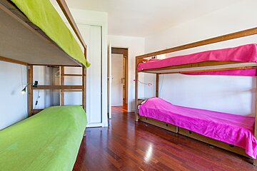 A bunk bed with a green blanket and a pink blanket