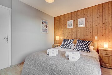 A bedroom with wood paneling and a bed with polka dot pillows