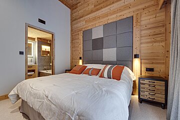 A bedroom with wooden walls and a large bed