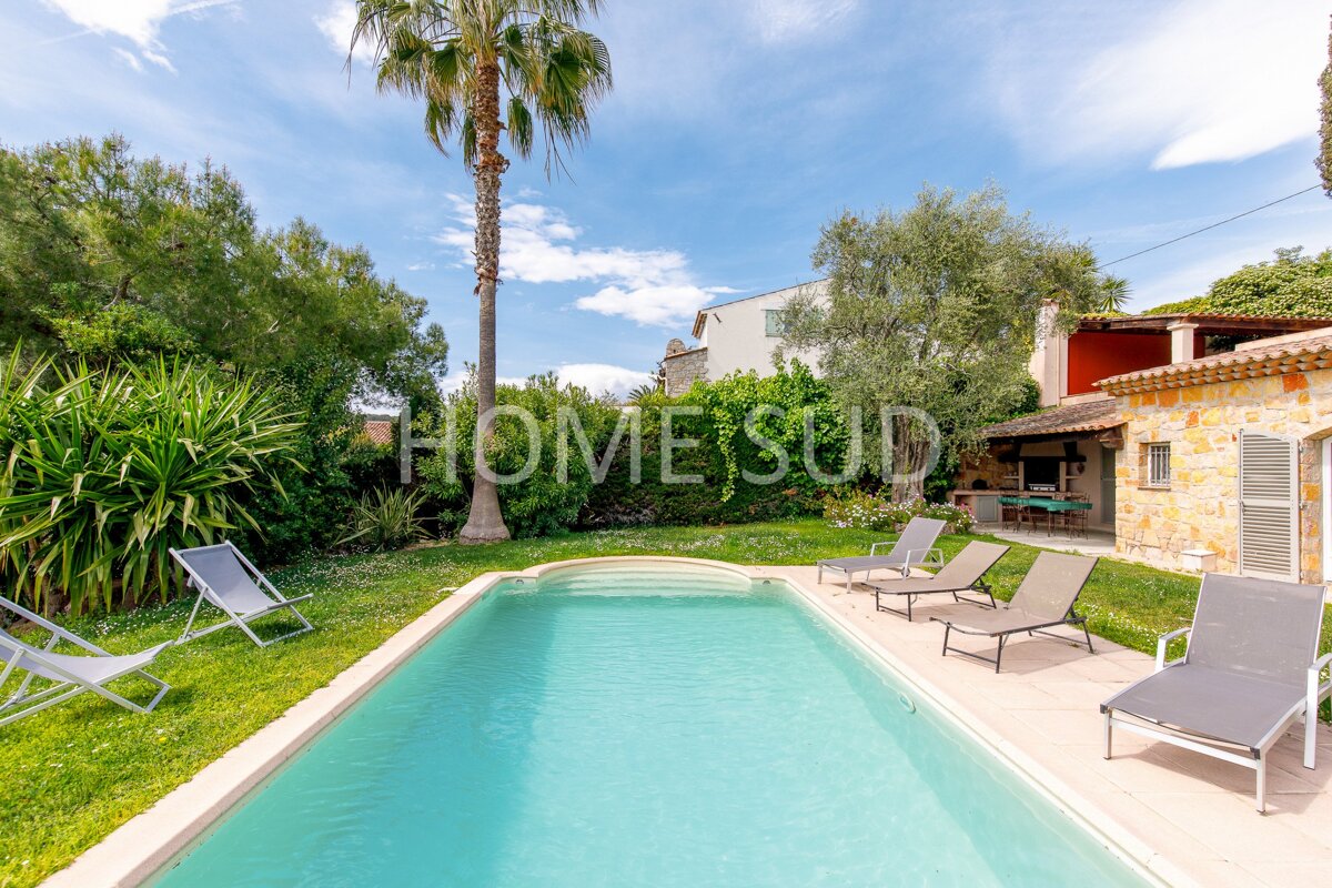 A large swimming pool is surrounded by lawn chairs and palm trees and is for sale by home sud
