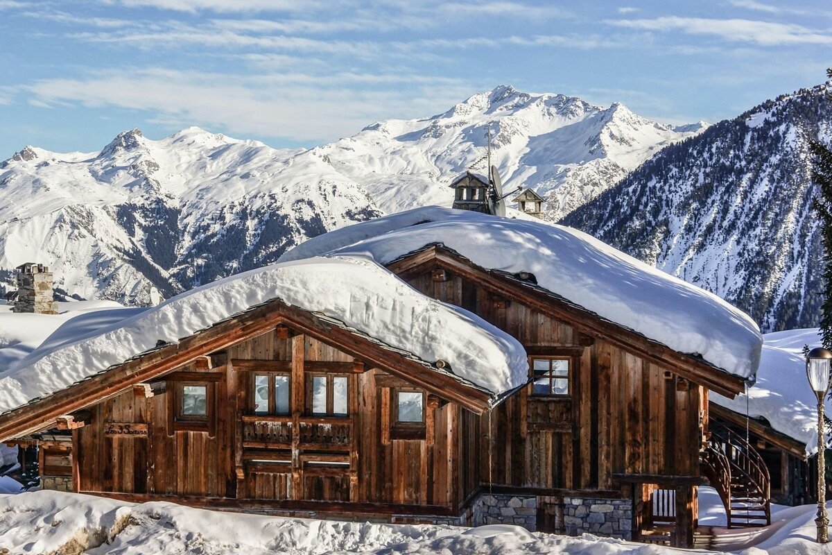 A snow covered cabin with mountains in the background