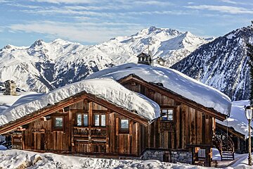 A snow covered cabin with mountains in the background