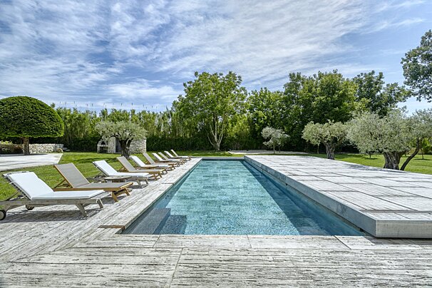 A large swimming pool surrounded by lawn chairs on a sunny day