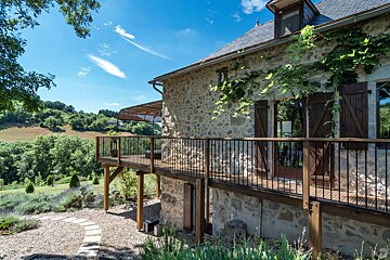 A stone house with a wooden deck and shutters