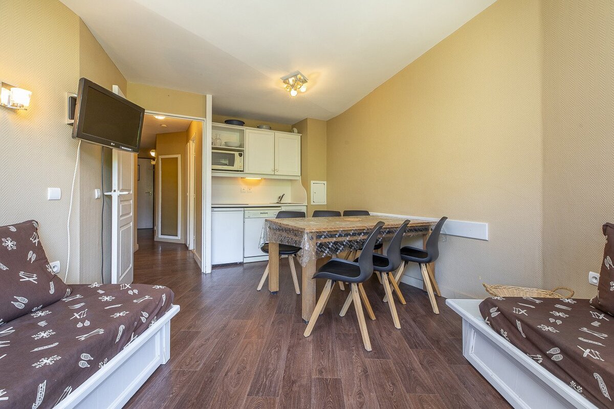 A living room with a table and chairs and a flat screen tv