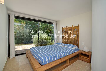 A bedroom with a bed and a screen that says made in janssens provence immobilier