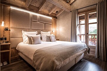 A bedroom with a teddy bear on the bed