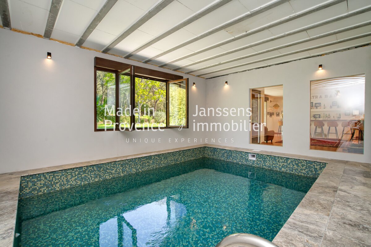 A large indoor pool with the words janssens immobilier on the wall