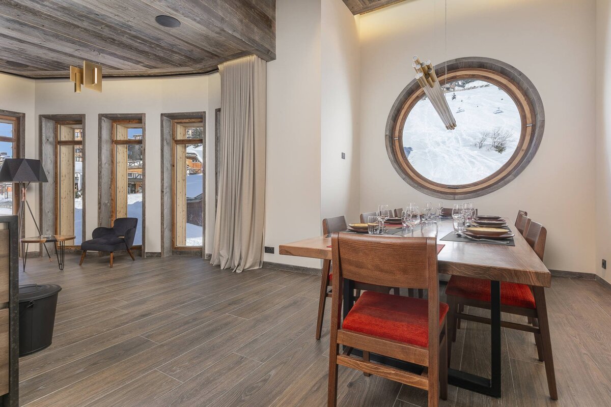 A dining room with a round window and a wooden table