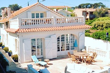A white house with a red tile roof and white shutters