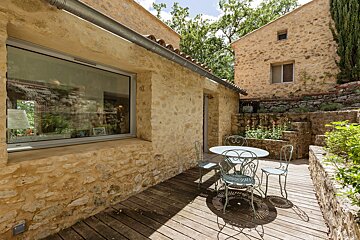 A patio with a table and chairs in front of a stone building